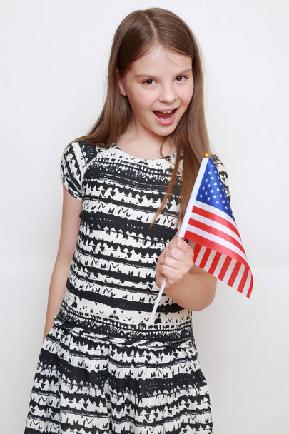 little girl holding USA flag in studio - Фото, изображение