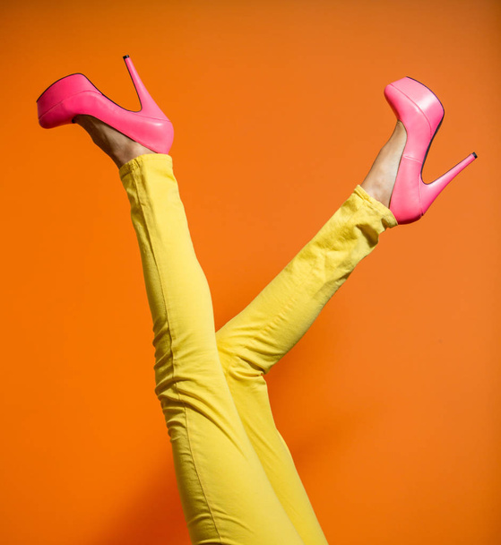 Female legs wearing high heels over bright orange background - Фото, зображення