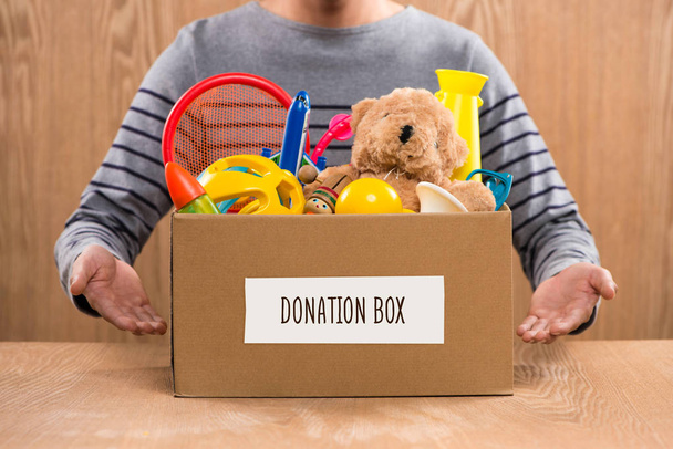 волонтер кладе іграшки в коробку
 - Фото, зображення
