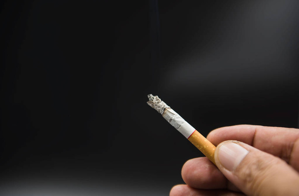 Cigaretta a kezében a fekete háttér  - Fotó, kép