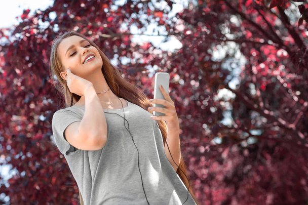 A joyful fantastic girl with a phone on a colorful background. A pretty girl listening to a cheerful music. Happiness, beauty, peace concept.  - Photo, image
