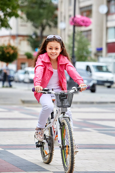 Söpö lapsi tyttö sininen kypärä menossa ratsastaa hänen pyörä
 - Valokuva, kuva
