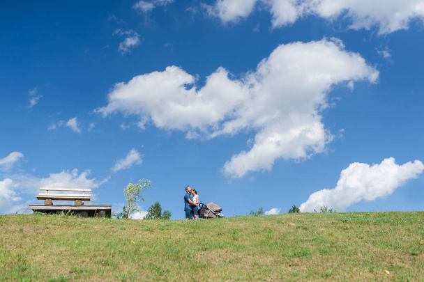 Familia feliz con el bebé en el campo. Campo verde bajo el cielo azul
. - Foto, imagen