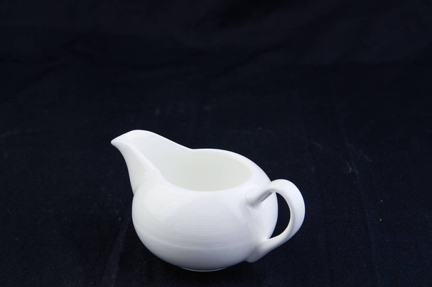 Isolate pouring milk, tea pot, kettle on black background.With work path
. - Фото, изображение