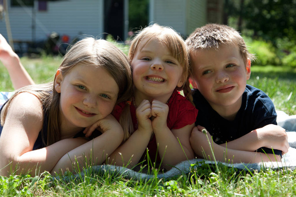 drie broers en zussen buiten in het gras  - Foto, afbeelding