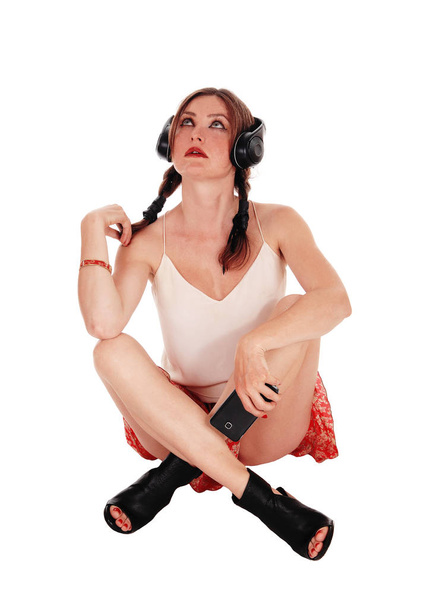 Nő ül az fülhallgató emeleten. - Fotó, kép