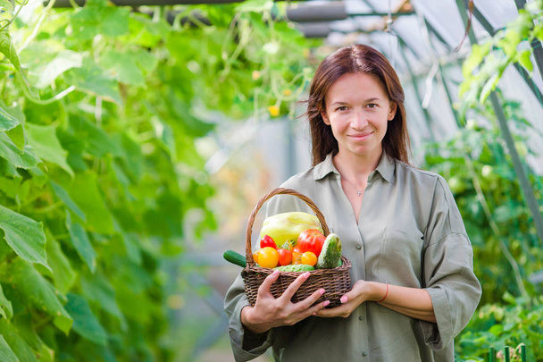 緑の野菜は温室のバスケットを持つ若い女性。収穫時期 - 写真・画像