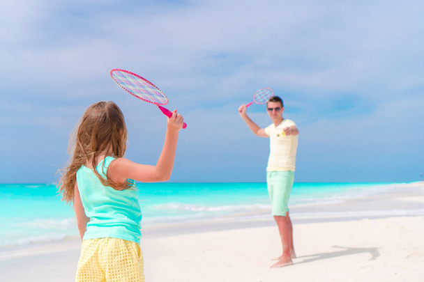 Little girl playing tennis with father on white tropical beach - Photo, Image