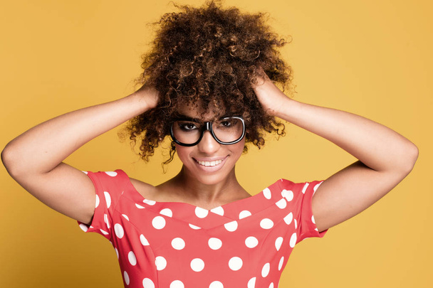 African american girl in eyeglasses on yellow background. - Foto, afbeelding