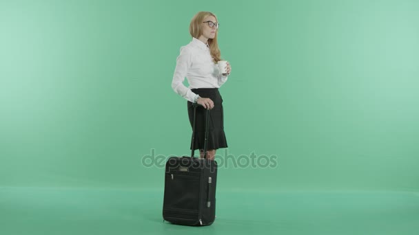 a woman in glasses stands with the luggage and coffee - Video, Çekim