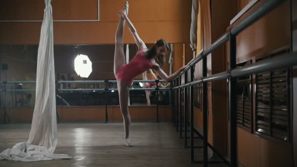 Mooi meisje toont de flexibiliteit van het lichaam aan de balie van ballet - Video