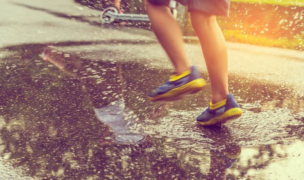 Vintage Ton Bild von Jungen läuft auf nasser Straße nach Regen. (Schwerpunkt Boden) - Foto, Bild