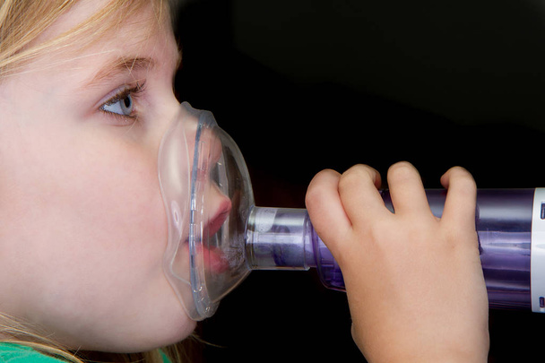 Menina tentando tratar sua asma com um hailer
 - Foto, Imagem