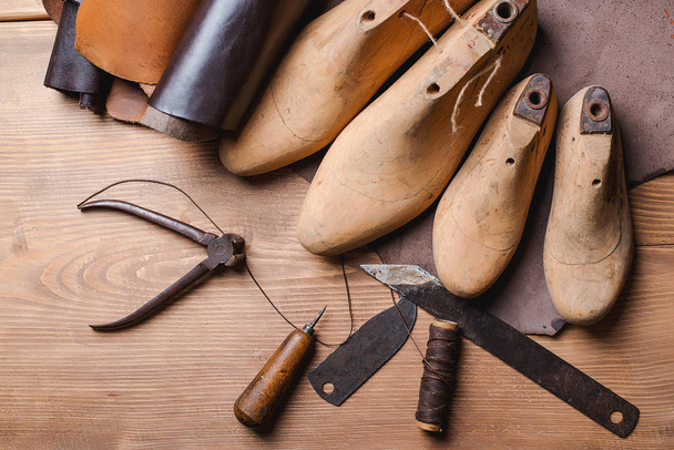 Cobbler tools in workshop on the wooden table . Top view. - 写真・画像