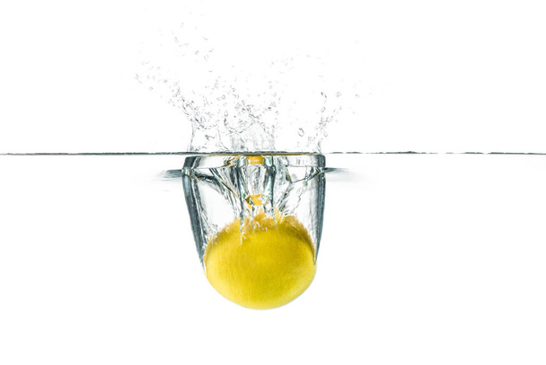 Fresh lemon dropped into the water with water splash on a white  - Фото, изображение