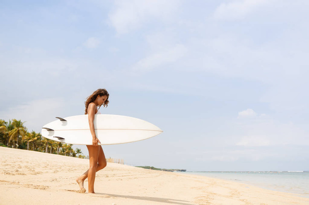 Beautiful sporty surfer girl at the beach. - Фото, изображение