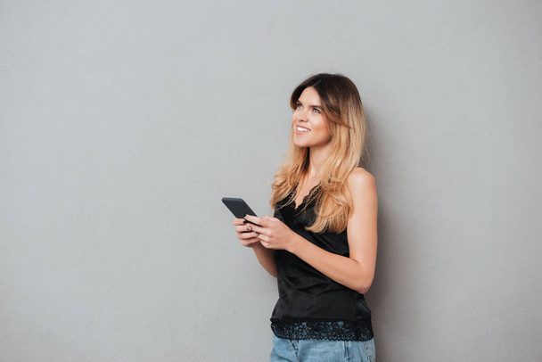 Jeune femme tenant un téléphone portable et regardant vers le haut à l'espace de copie
 - Photo, image