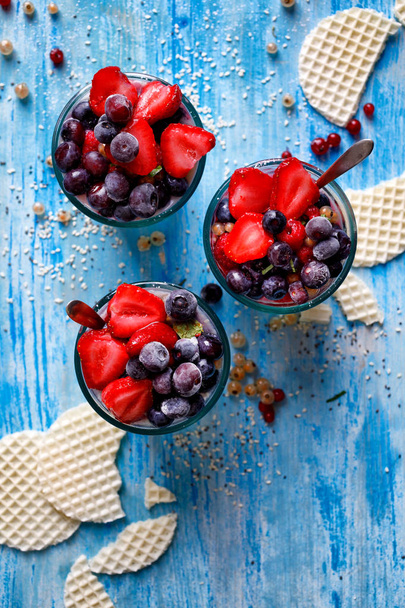 Aardbei en Blueberry dessert met toevoeging Chia zaden en sesamzaden in de glazen op een houten blauwe tafel, gezond dieet concept - Foto, afbeelding