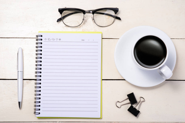 Fehér set. Toll, szemüvegek, kávé- és notebook az asztalon. Szemközti nézet. - Fotó, kép