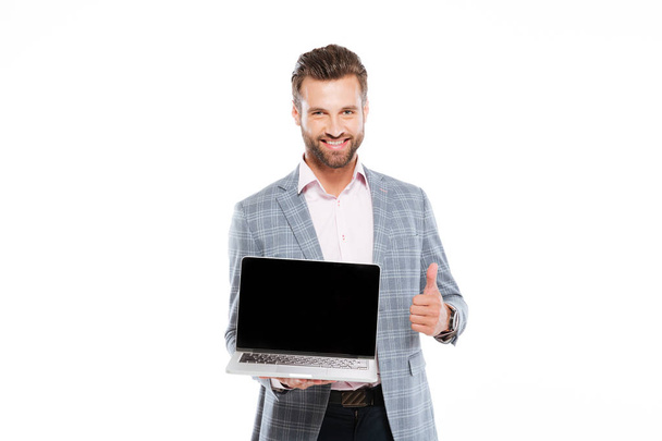 Cheerful young man holding laptop showing thumbs up. - 写真・画像