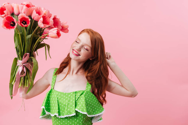 Image of Smiling ginger woman holding bouquet flowers - Фото, изображение
