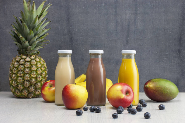 different bottles of juice with fruits on wooden table - Photo, Image