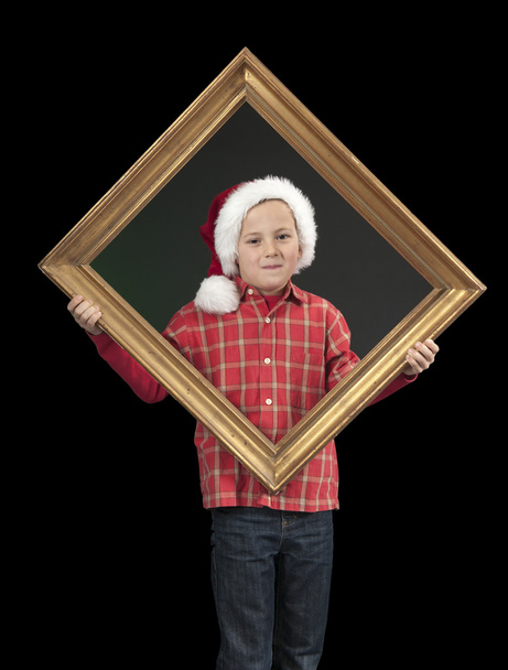 Boy with xmas hat holding a golden frame, on black - Foto, immagini