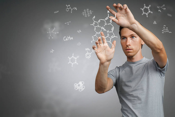 Man scientist working with chemical formulas on gray background. - Zdjęcie, obraz
