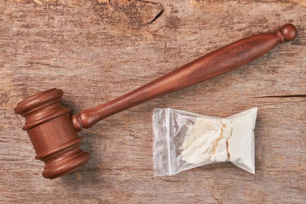 Packet of drugs, gavel, wooden background. - Photo, Image