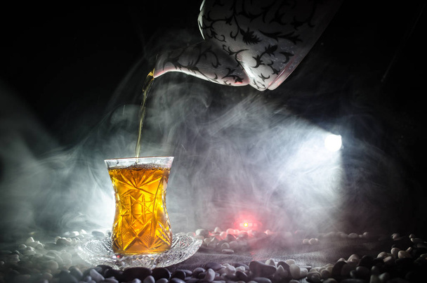 Turkin Azerbaidzanin teetä perinteisessä lasissa ja potin mustalla taustalla valot ja savu. Armudu perinteinen kuppi
 - Valokuva, kuva