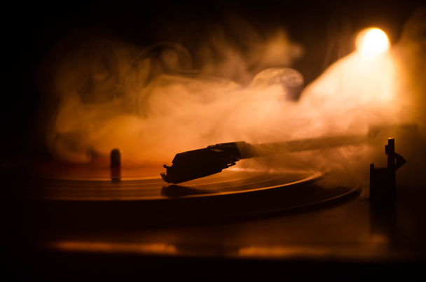 Turntable vinyl record player. Retro audio equipment for disc jockey. Sound technology for DJ to mix & play music. Vinyl record being played against burning fire background with smoke. Vintage - Photo, Image