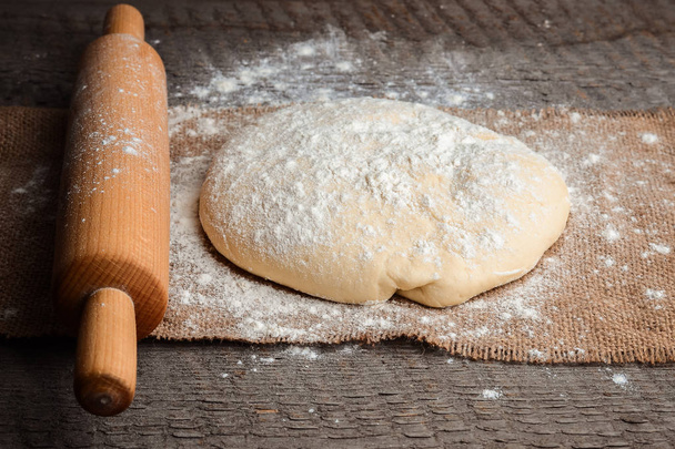 Ball of dough and rolling pin on rustic background - Photo, Image