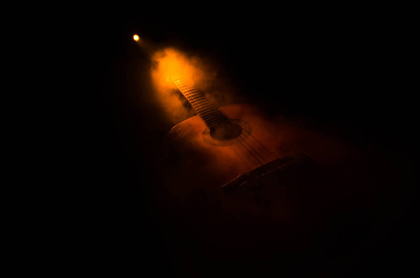 Концепция музыки. Акустическая гитара изолирована на тёмном фоне под лучом света с дымом с копировальным пространством. Гитарные струны, закройте. Выборочный фокус. Огненные эффекты
 - Фото, изображение