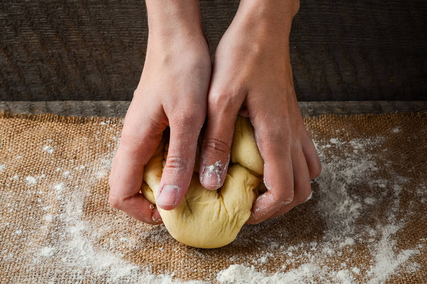 Hands prepare dough on a dark background - Valokuva, kuva