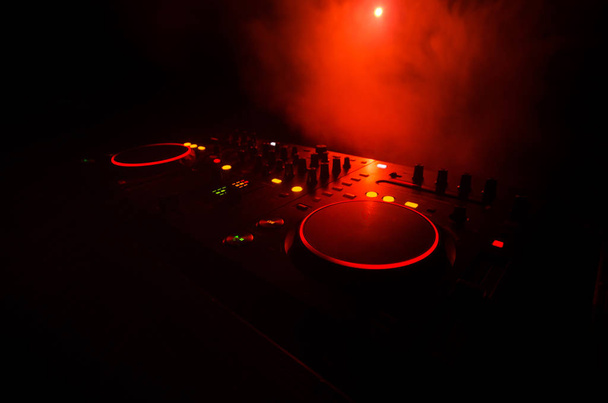 DJ iplik, karıştırma ve bir gece kulübünde tırmalamak, eller DJ 's dj güverte, strobe ışıklar ve sis, seçici odak çeşitli parça denetimlere tweak - Fotoğraf, Görsel