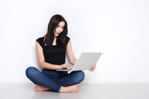 Vrouw met laptop zittend op de vloer studio - Foto, afbeelding