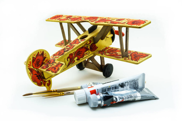 Іграшковий літак, пофарбований у стилі хохломи, акрилові фарби та пензлі на білому тлі
 - Фото, зображення