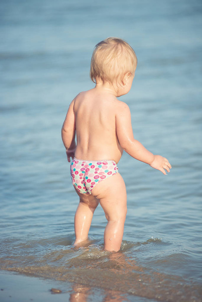 Cute baby playing on the sandy beach and in sea water. - Foto, imagen