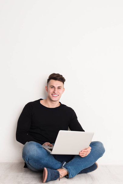 Улыбающийся молодой человек фрилансер в повседневной жизни с ноутбуком
 - Фото, изображение