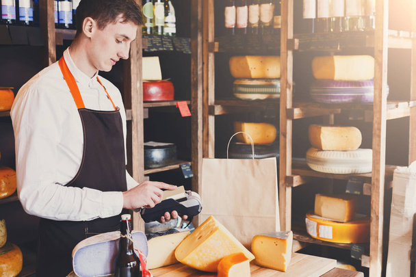 Male cheese shop assistant swipe credit card - Фото, зображення