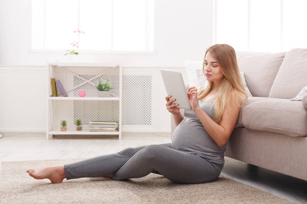 Ευτυχισμένη γυναίκα έγκυος χρησιμοποιώντας ψηφιακό tablet. - Φωτογραφία, εικόνα