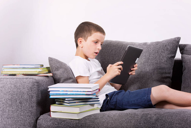 Boy using a tablet PC on the sofa.  - Foto, immagini