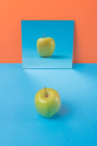 Apple on blue table isolated over orange background - Photo, image
