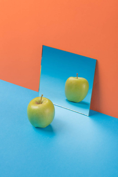 Apple on blue table isolated over orange background - Photo, image