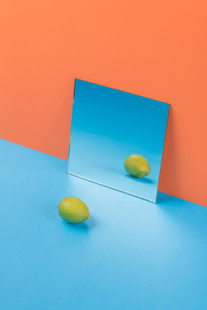 Lime on blue table isolated over orange background - Foto, afbeelding