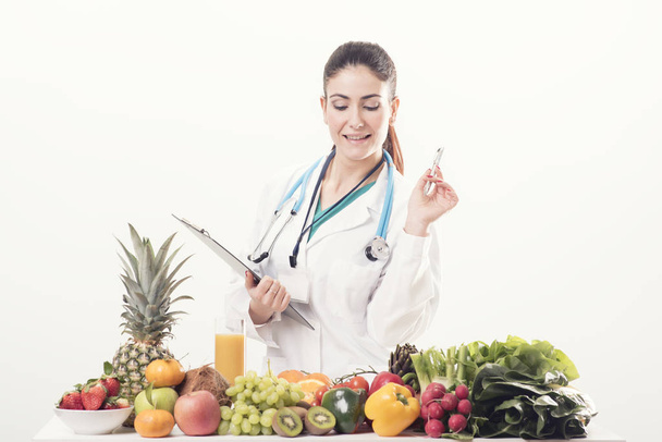 Médico dietista en su escritorio con frutas
 - Foto, Imagen