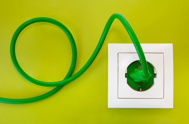 Enchufe de alimentación verde en toma de corriente blanca
 - Foto, Imagen
