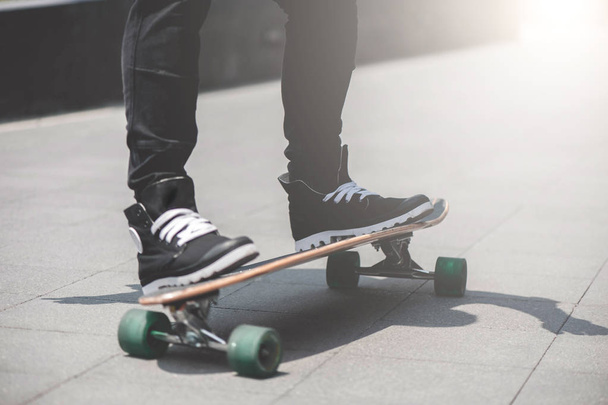 Close up of skater's legs on the longboard riding at the street in outdoors - Photo, image
