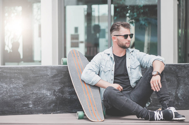 Man sit with skateboard. - Foto, imagen