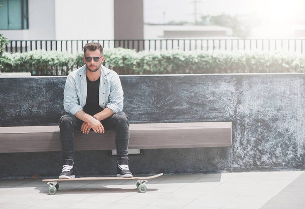 Man sit with skateboard. - 写真・画像